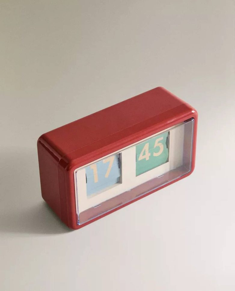 Crveni retro budilnik sa preklopnim brojevima na neutralnoj podlozi