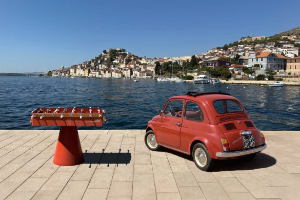 Crveni Fiat 500 pored dizajnerskog stola za stoni fudbal na obali mora