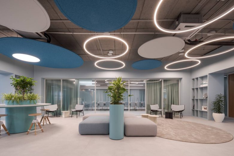Relaks zona sa plavim akustičnim plafonskim panelima, kružnim svetlima i biljkama u Aneksu Ložionice u Beogradu