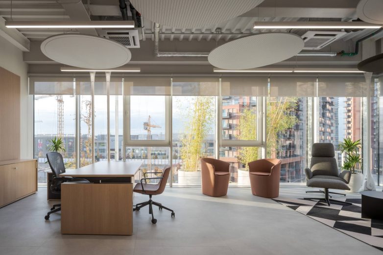 Kancelarijski prostor sa radnim stolom, foteljama i velikim prozorima sa pogledom u Aneksu Ložionice u Beogradu