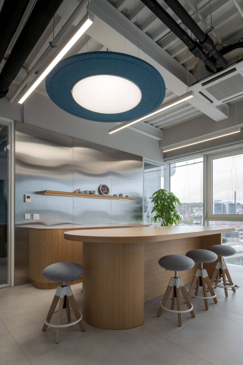 Kuhinjski prostor sa drvenim šankom, visokim stolicama i akustičnim plafonskim panelom u Aneksu Ložionice u Beogradu
