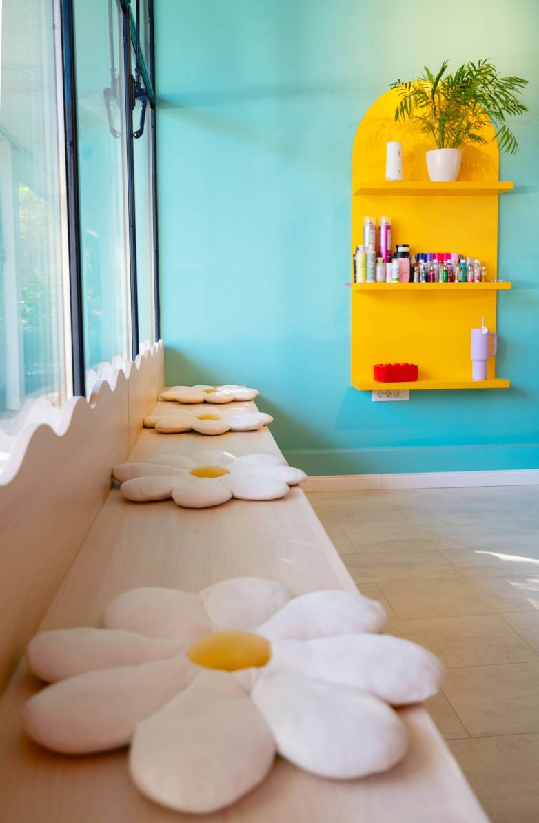 Drvena klupa uz prozor sa jastucima u obliku cveta u šarenom enterijeru dečjeg salona