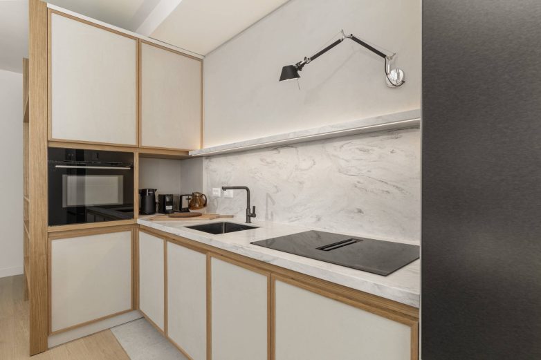 Radna zona kuhinje sa sudoperom, ugradnom pločom i mermernim zidnim oblogama u stanu u Beogradu na vodi