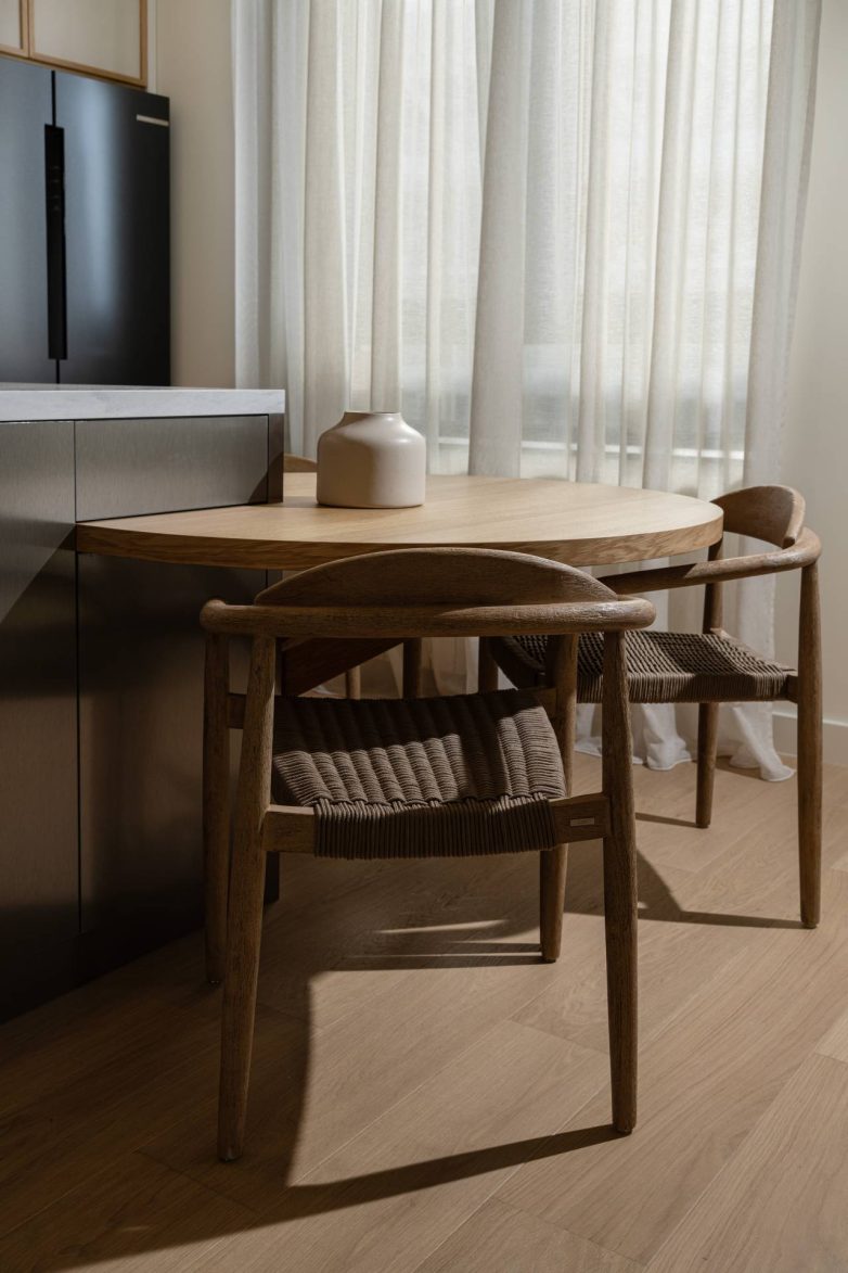 Drveni trpezarijski sto i stolice pored kuhinjskog ostrva u modernom enterijeru