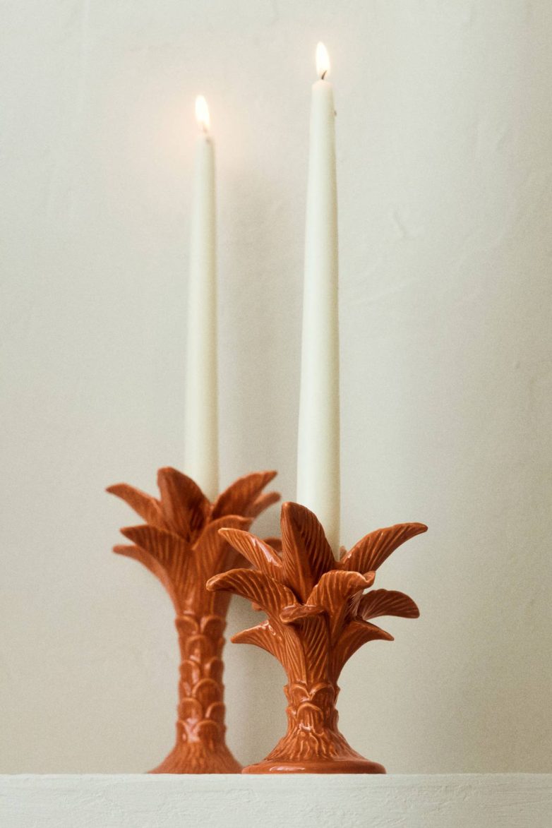 Dva keramička svećnjaka u obliku palme sa belim svećama postavljena na svetloj podlozi