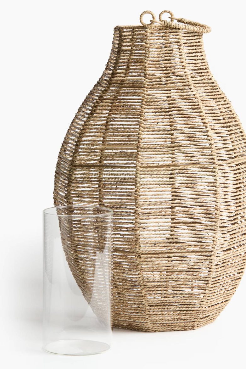 Veliki fenjer od pletene morske trave sa staklenim cilindrom za sveću na svetloj pozadini