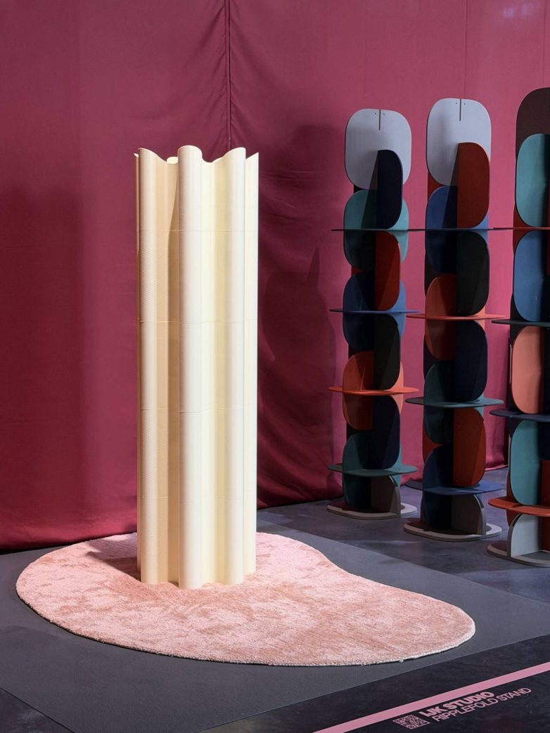 Stalak za odeću u obliku drapirane forme postavljen na tepihu u izložbenom prostoru tokom Design Weeka u Milanu