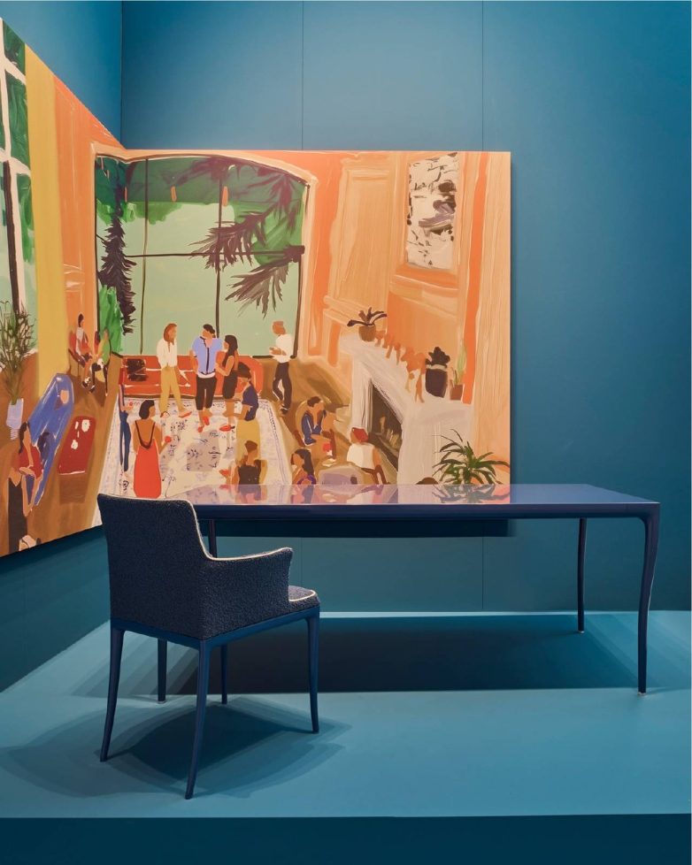 Plavi enterijer Kartell štanda sa radnim stolom, stolicom i velikom slikom prostora generisanom veštačkom inteligencijom