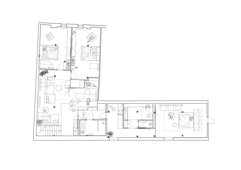 Otvoren enterijer potkrovlja sa drvenim gredama, belim sofama, crnim kuhinjskim blokom i kamenim zidom u pozadini