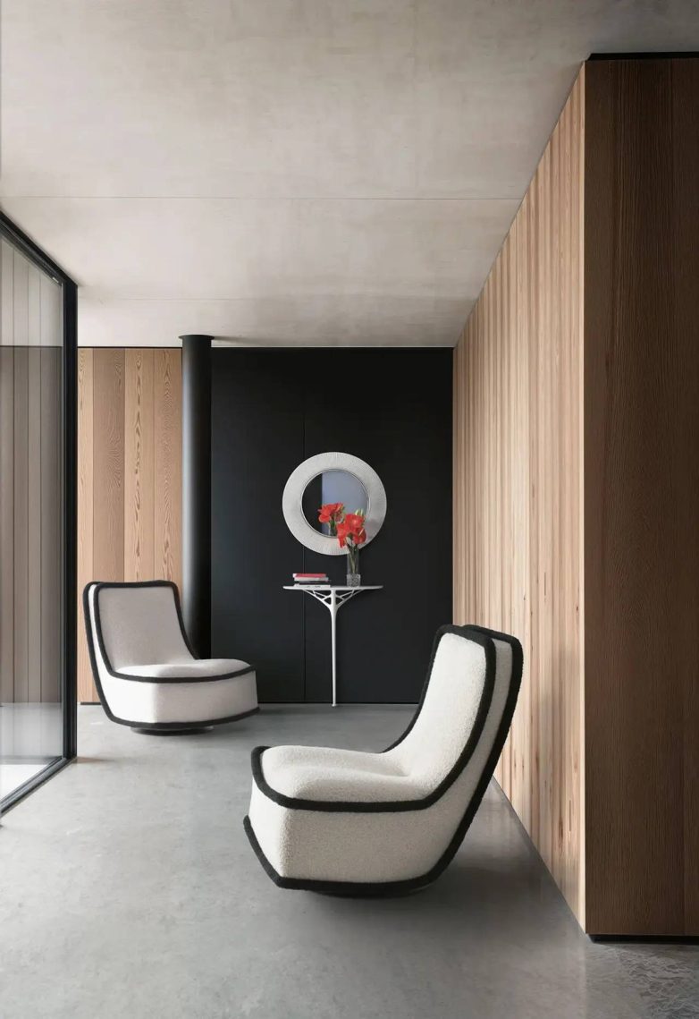 Fotelja Kartell obložena bukle tkaninom sa crnim ivicama u minimalističkom enterijeru sa drvenim panelima