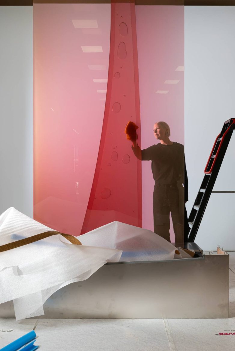 Osoba čisti veliku crvenu staklenu formu tokom postavke instalacije za Salone Raritas u Milanu