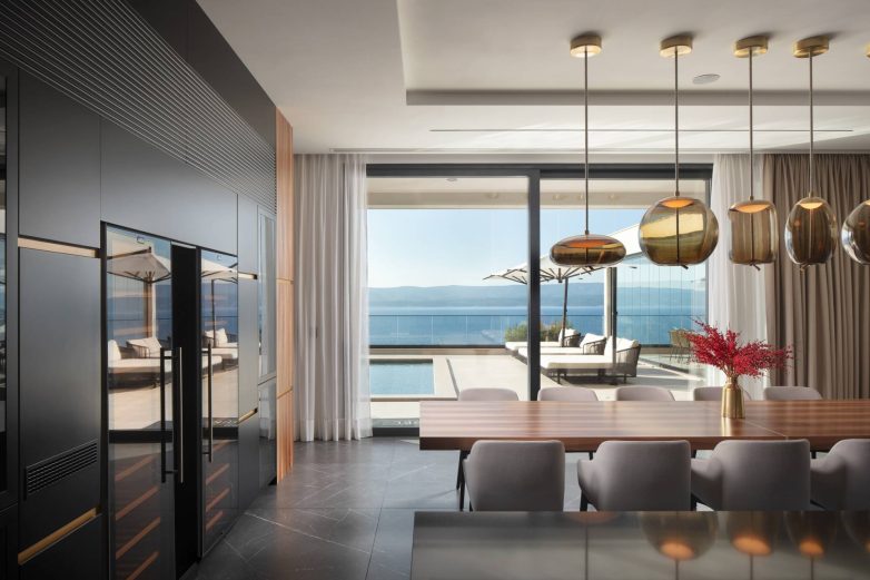 Kuhinja i trpezarija u vili Mirabel sa velikim staklenim zidovima i pogledom na bazen i more