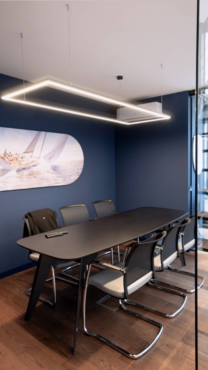 Sala za sastanke u salonu Yachting One u Beogradu sa velikim stolom, crnim stolicama i zidom u tamnoplavoj boji.