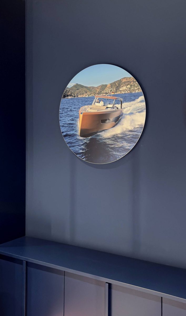 Zidna grafika u salonu Yachting One u Beogradu koja prikazuje motorni čamac na moru postavljena na tamnoplavom zidu.