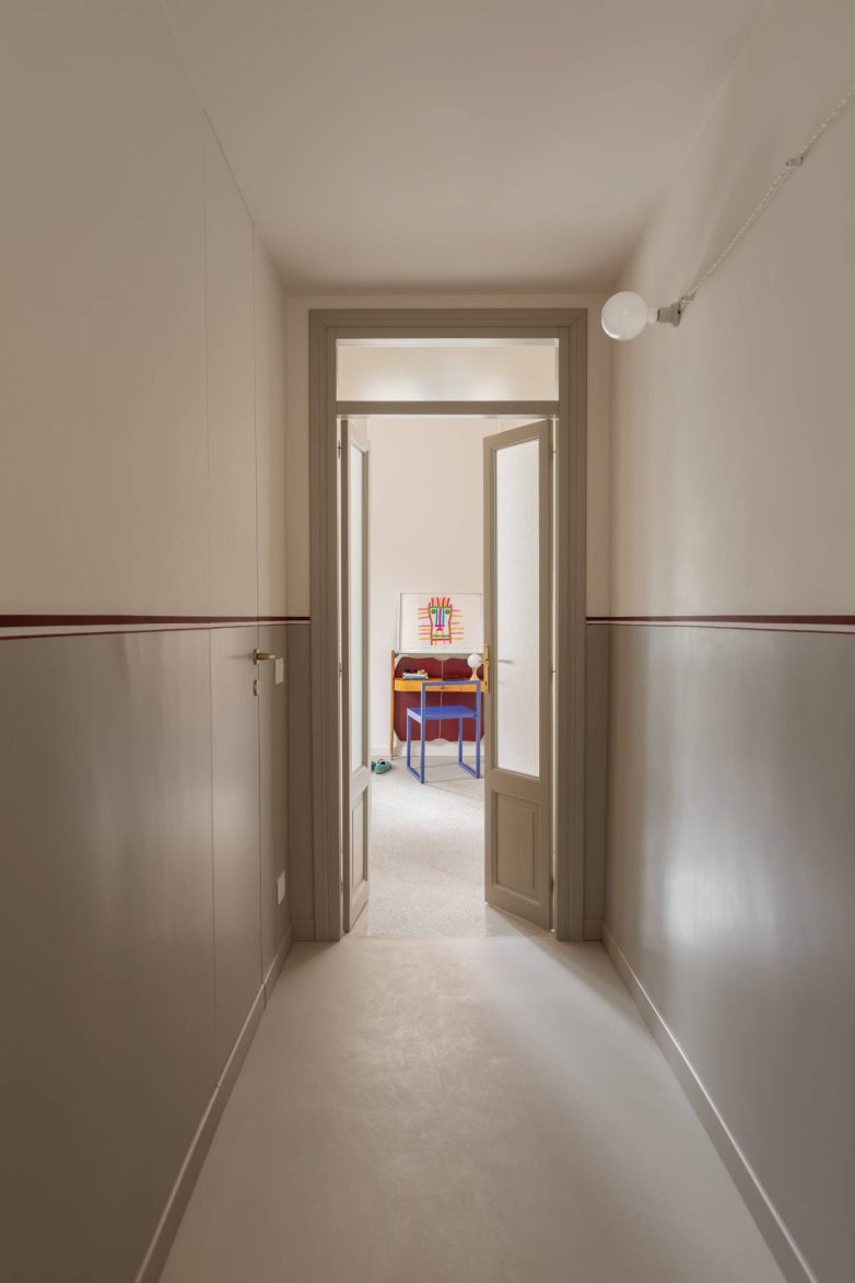 Hodnik u stanu Casa Garbatella u Rimu ima tanku crvenu liniju i vrata koja vode ka spavaćoj sobi.