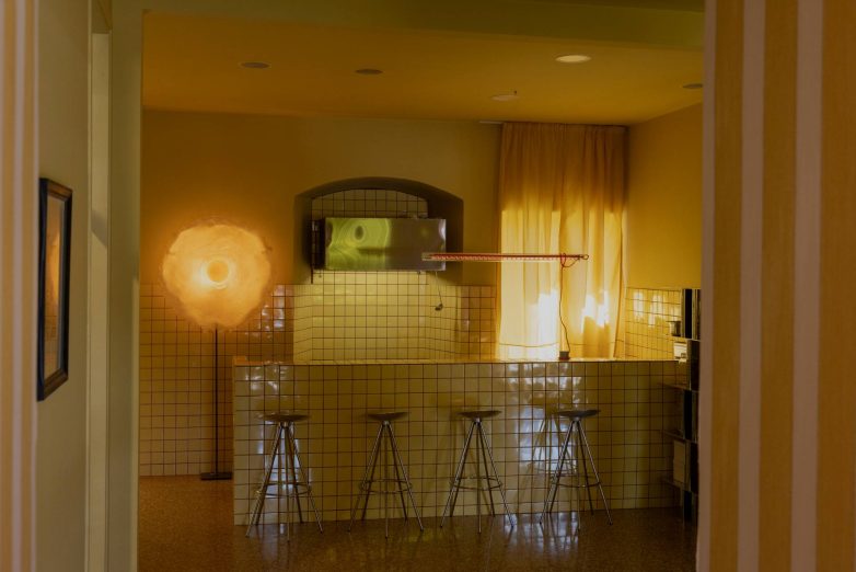 Detalj enterijera Cirkus Protokola u Rijeci sa šankom obloženim pločicama, barskim stolicama, zavesom i upečatljivom okruglom "Egg Lamp" lampom.