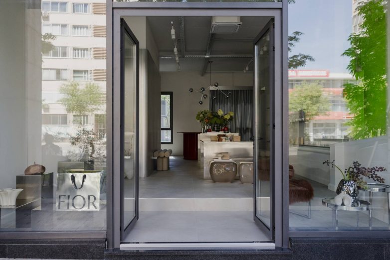 Kroz veliki izlog "concept store"-a Fior u Splitu vidi se enterijer sa centralnom radnom površinom, cvećem, neutralnim tonovima i otvorenim ulazom.
