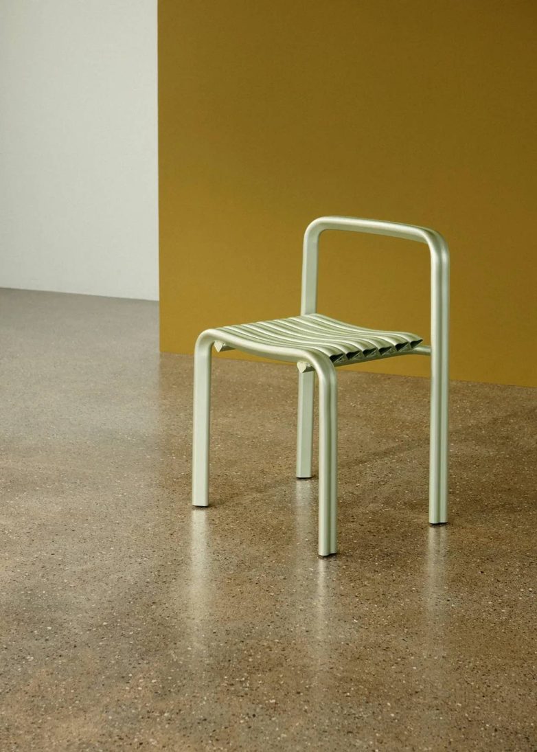 Stolica Muuto Close to Heart prikazana je u minimalističkom enterijeru sa maslinastim zidom i podom od poliranog betona.