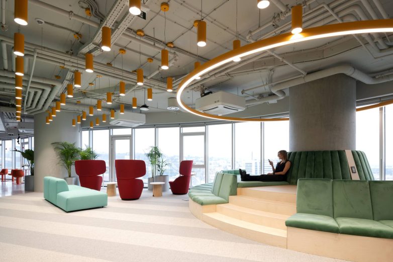 "Lounge" zona u kancelariji kompanije Serb Tech u Beogradu ima stepenasto sedenje, zelene tapacirane elemente, crvene fotelje i kružnu rasvetu.