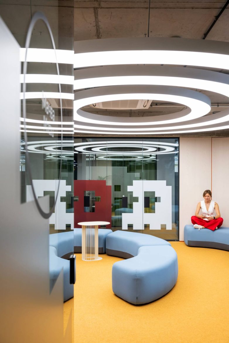 "Lounge" zona u kancelariji kompanije Serb Tech u Beogradu ima žuti pod, svetloplave modularne sofe, kružnu rasvetu i pikselizovanu grafiku na staklu.