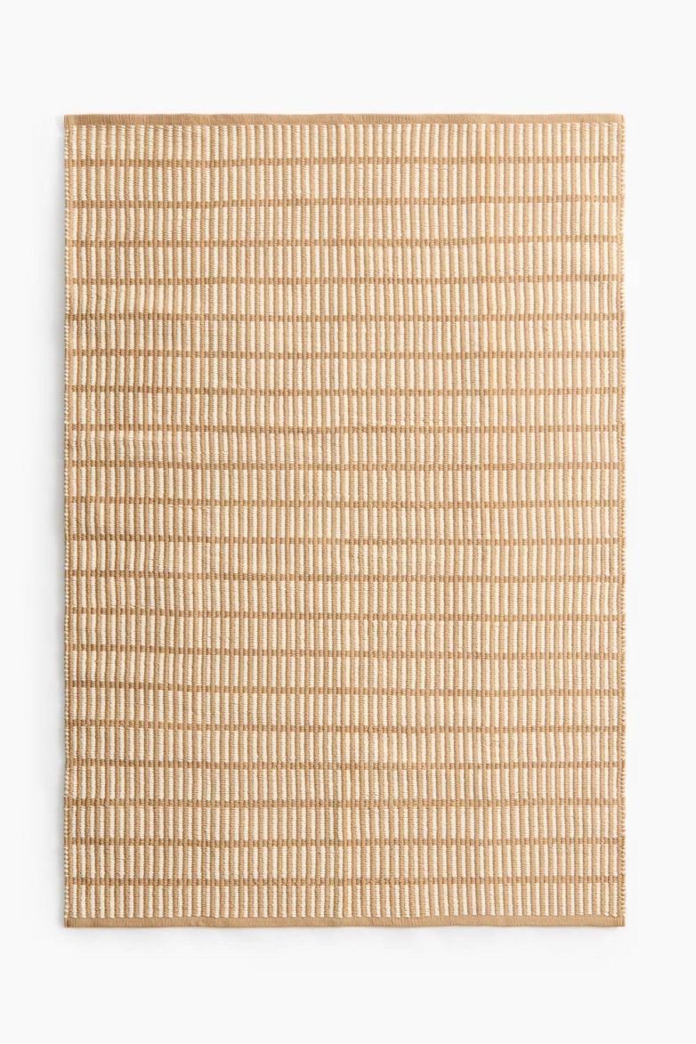 Bež tepih za terasu iz H&M Home ponude ima prugastu teksturu i neutralan izgled.