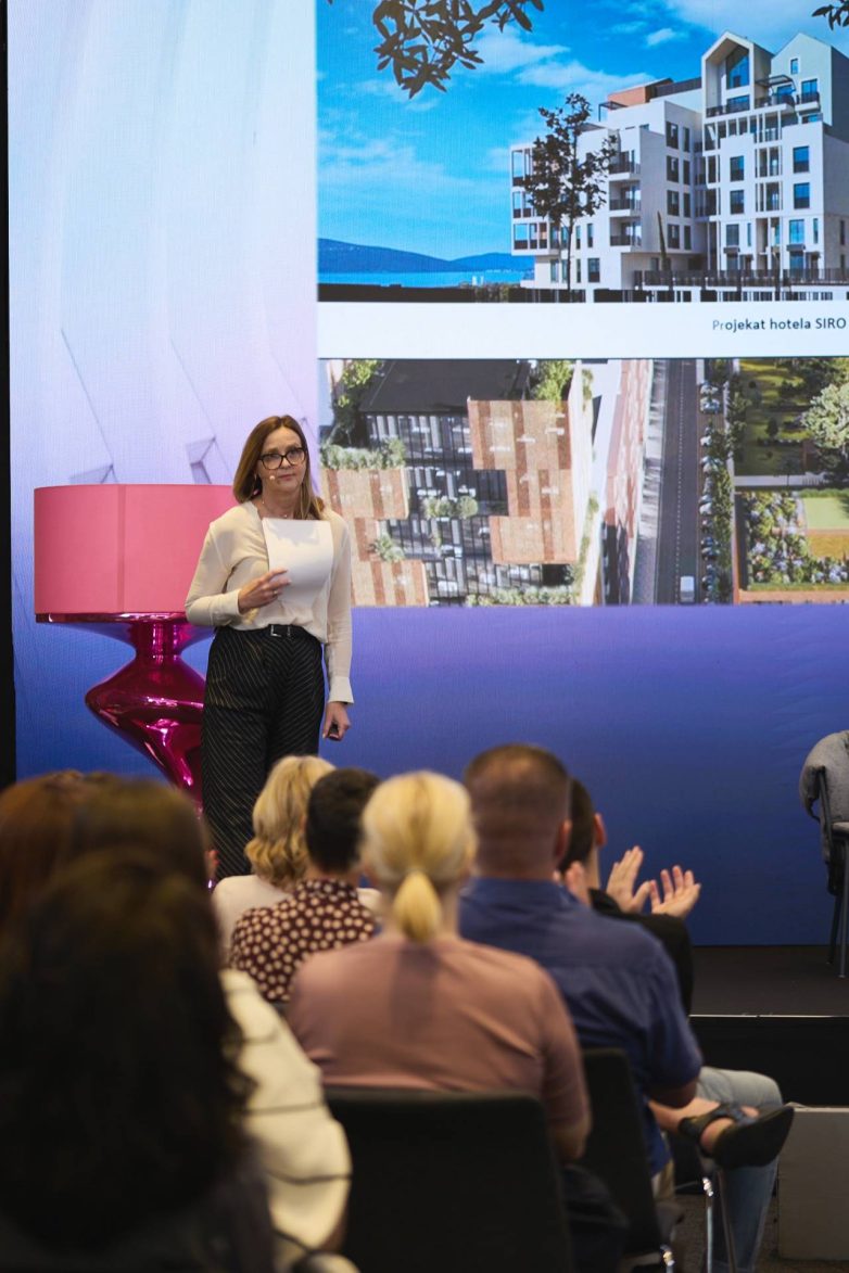 Arhitektkinja Anja Ivana Milić drži prezentaciju na konferenciji ArcHERtecture / SHEngineering u Beogradu, uz prikaz arhitektonskih projekata na velikom ekranu