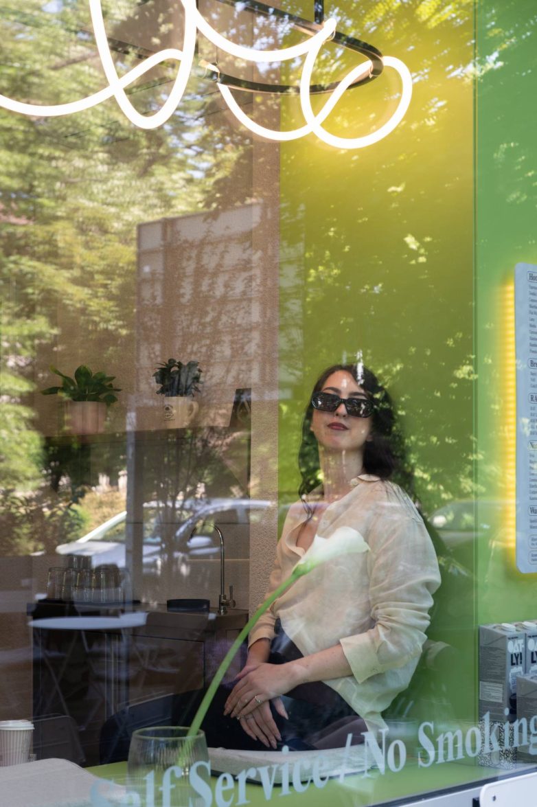 Pogled kroz izlog kafeterije Artist u Zemunu sa zelenim zidom i neonskom rasvetom