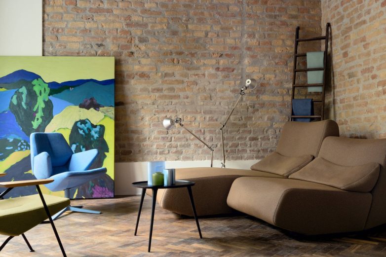 Enterijer FOUND.store pop-up prodavnice u Beogradu sa dizajnerskom sofom, foteljama, stočićem, zidom od opeke i slikom velikog formata