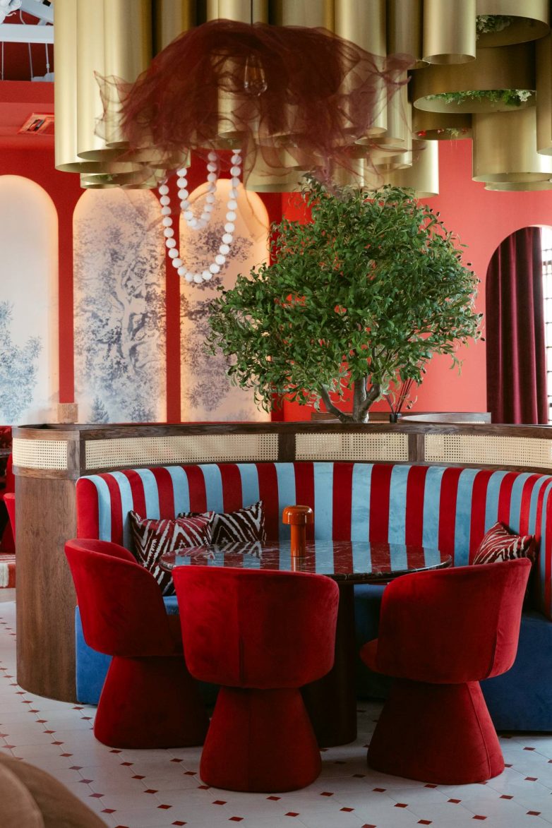 Kružni separe restorana GOAT u Banjoj Luci sa crveno-plavim prugastim tapacirungom, crvenim stolicama, mermernim stolom, drvetom u enterijeru i zlatnim plafonskim elementima, projekat studija JB architect