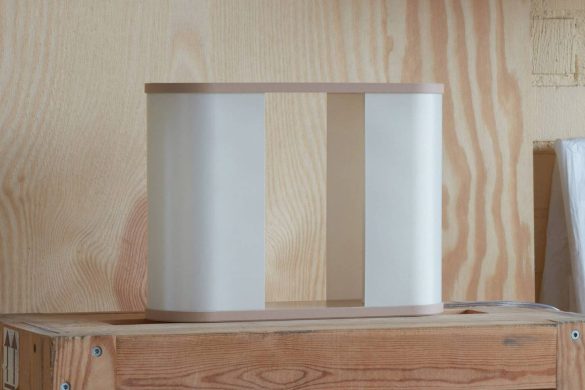Minimalistička stona lampa sa zaobljenim ramom i centralnim otvorom na drvenoj površini
