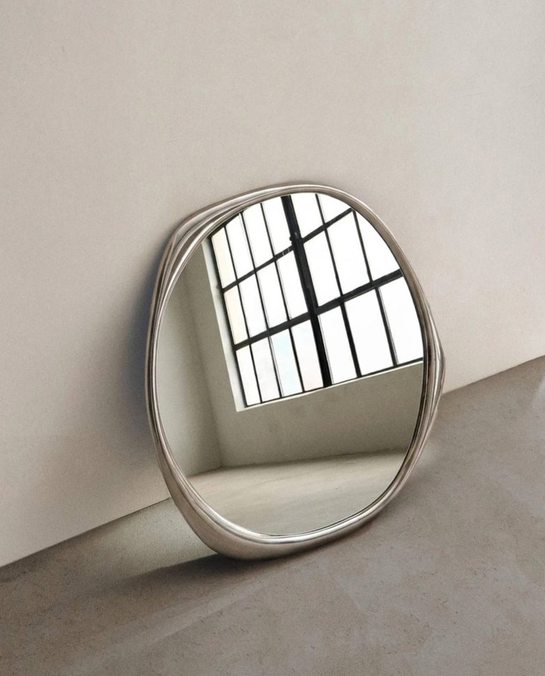 Nepravilno ogledalo sa aluminijumskim porubom u minimalističkom enterijeru