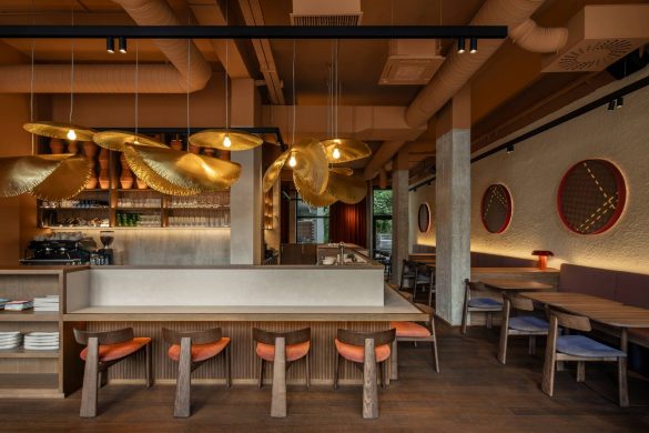 Enterijer azijskog restorana Lucky Cat u Ljubljani sa centralnim barom, mesinganim visilicama i toplim terakota tonovima