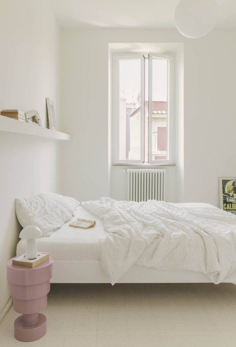 Svetla bela spavaća soba sa roze noćnim stočićem i prozorom u renoviranom stanu Casa Tahiti u Rimu
